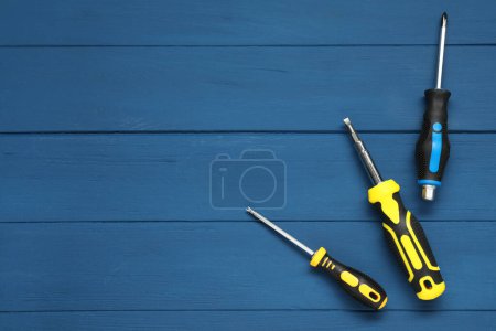Set of screwdrivers on blue wooden table, top view. Space for text