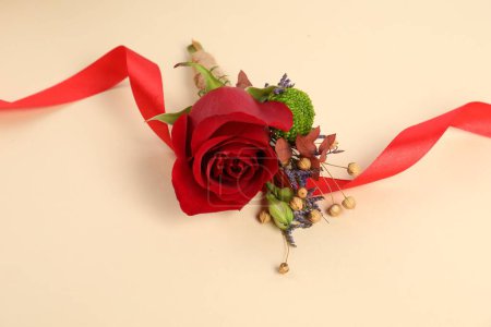 Téléchargez les photos : Boutonnière élégante avec rose rouge et ruban sur fond beige - en image libre de droit
