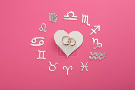 Foto de Signos del zodíaco, corazón y anillos de boda sobre fondo rosa, planas - Imagen libre de derechos