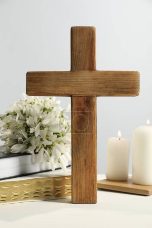 Photo for Burning church candles, wooden cross, ecclesiastical books and flowers on white table - Royalty Free Image