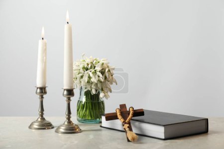 Photo for Church candles, wooden cross, rosary beads, Bible and flowers on marble table. Space for text - Royalty Free Image