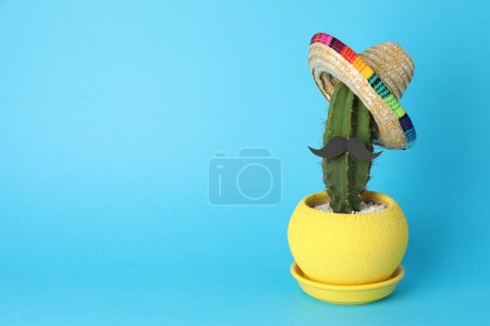 Téléchargez les photos : Cactus avec chapeau de sombrero mexicain et fausse moustache sur fond bleu clair, espace pour le texte - en image libre de droit