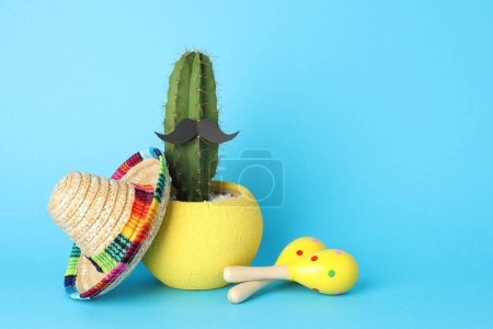 Téléchargez les photos : Chapeau sombrero mexicain, cactus avec fausse moustache et maracas sur fond bleu clair, espace pour le texte - en image libre de droit