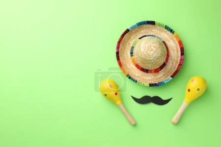 Téléchargez les photos : Chapeau de sombrero mexicain, fausse moustache et maracas sur fond vert, plat. Espace pour le texte - en image libre de droit