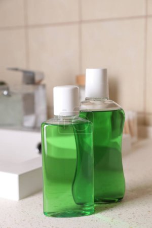 Foto de Enjuagues bucales frescos en botellas en la encimera en el baño, primer plano - Imagen libre de derechos