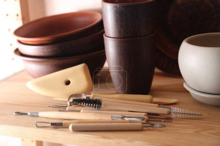 Set verschiedener Bastelwerkzeuge und Tonschalen auf Holztisch in Werkstatt