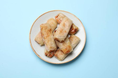 Fried spring rolls on light blue table, top view