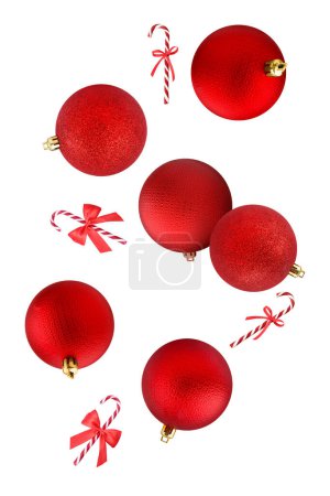 Foto de Bolas rojas de Navidad y bastones de caramelo cayendo sobre fondo blanco - Imagen libre de derechos