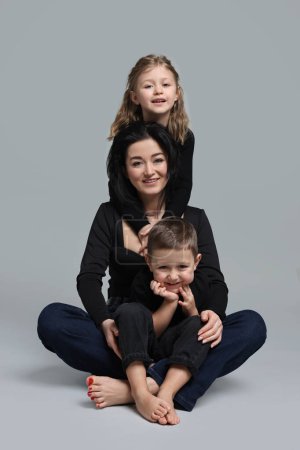 Kleine Kinder mit ihrer Mutter auf grauem Hintergrund