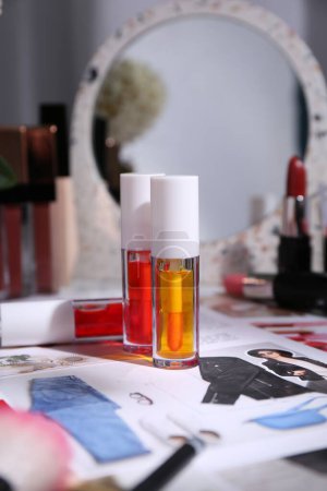 Foto de Brillante brillo labial entre los diferentes productos cosméticos y revista de moda en el interior de la mesa - Imagen libre de derechos