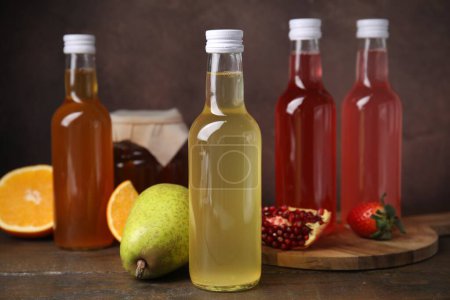 Köstliche Kombucha in Glasflaschen, Glas und frischem Obst auf Holztisch