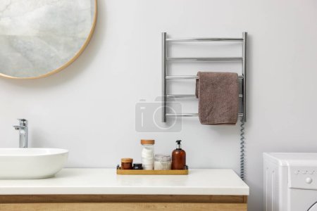 Stilvolles Badezimmerinterieur mit beheiztem Handtuchhalter und Kosmetikprodukten