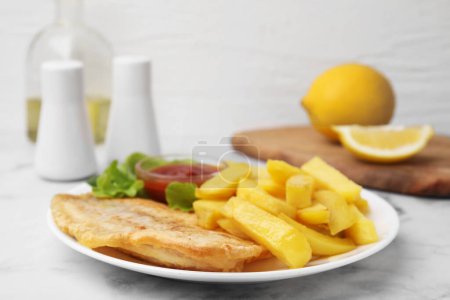Délicieux fish and chips avec ketchup et laitue sur table lumineuse, gros plan