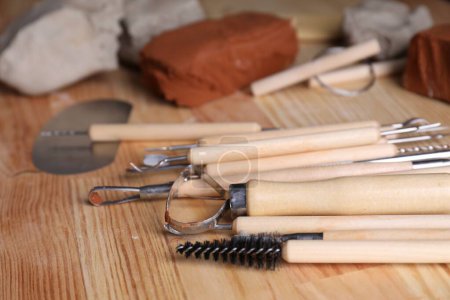 Clay and set of modeling tools on wooden table, closeup