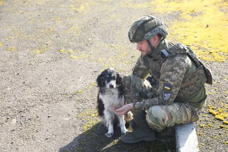 Ukrainischer Soldat mit streunendem Hund an einem sonnigen Tag im Freien. Raum für Text
