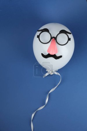 Téléchargez les photos : Visage d'homme en ballon, fausse moustache, nez et lunettes sur fond bleu, vue de dessus - en image libre de droit