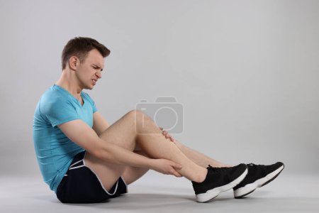 Photo for Man suffering from leg pain on grey background - Royalty Free Image