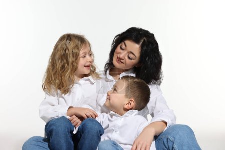 Kleine Kinder mit ihrer Mutter sitzen zusammen auf weißem Hintergrund
