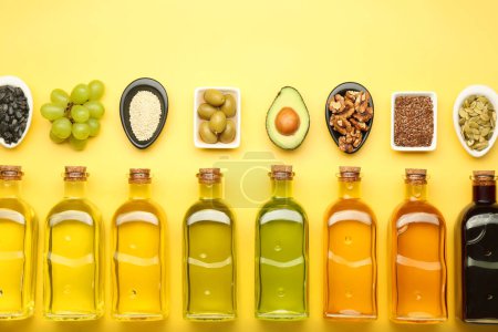 Foto de Grasas vegetales. Diferentes aceites en botellas de vidrio e ingredientes en la mesa amarilla, puesta plana - Imagen libre de derechos