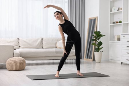Girl stretching on yoga mat at home. Janu Sirsasana pose variation