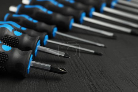 Set of screwdrivers on black wooden table, closeup
