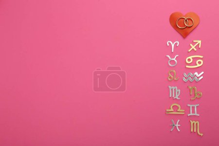Zodiac compatibility. Signs, wedding rings and red heart on pink background, flat lay. Space for text