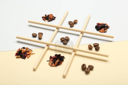 Tic tac toe Spiel mit Kaffeebohnen und trockenen Teeblättern auf farbigem Hintergrund
