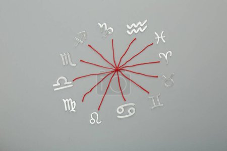 Foto de Compatibilidad con el zodiaco. Signos e hilos rojos sobre fondo gris, plano - Imagen libre de derechos