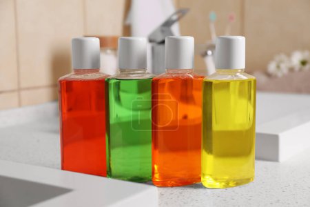 Fresh mouthwashes in bottles on countertop in bathroom, closeup