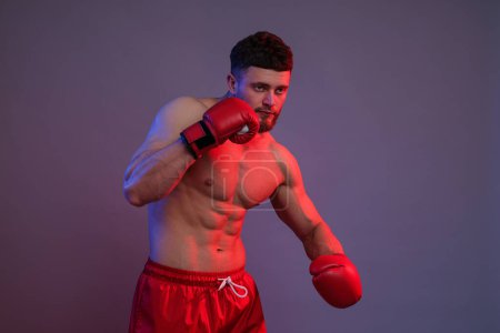 Téléchargez les photos : Homme en gants de boxe se battant sur fond de couleur - en image libre de droit