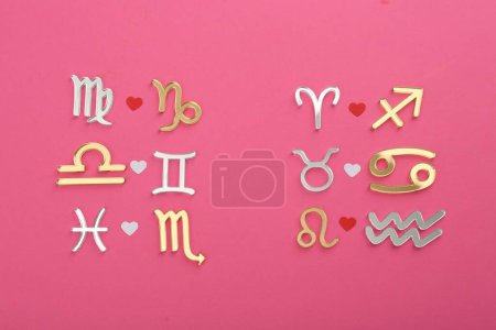 Zodiac signs compatibility on pink background, flat lay