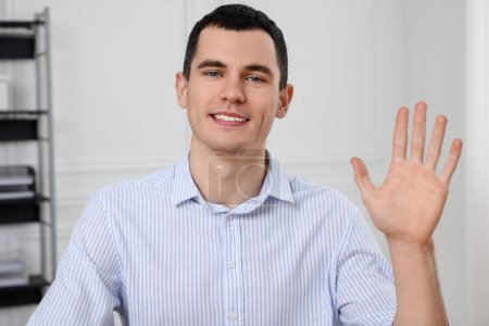 Foto de Hombre saludando mientras tiene chat de vídeo en la oficina, vista desde la cámara web - Imagen libre de derechos