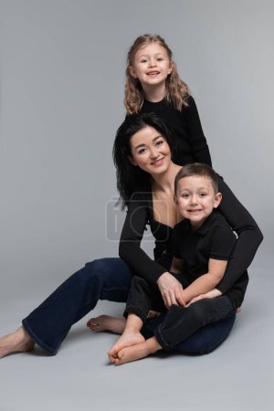 Kleine Kinder mit ihrer Mutter auf grauem Hintergrund