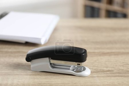 One stapler on wooden table indoors, closeup