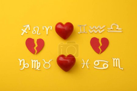 Zodiac compatibility. Signs with red whole and broken hearts on yellow background, flat lay