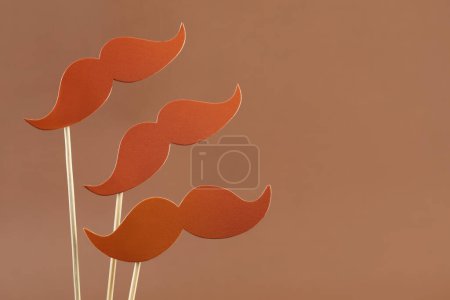 Téléchargez les photos : Faux papier moustaches accessoires de fête sur fond brun clair, espace pour le texte - en image libre de droit