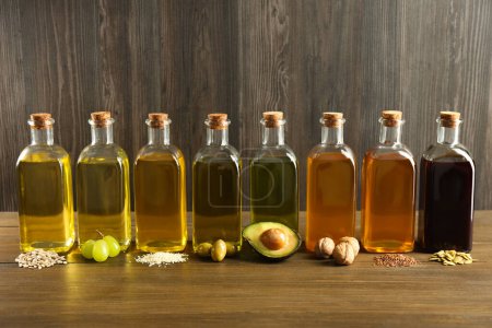 Photo for Vegetable fats. Different oils in glass bottles and ingredients on wooden table - Royalty Free Image