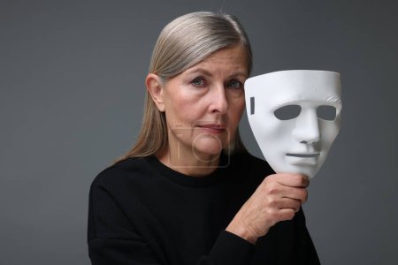 Photo for Multiple personality concept. Woman with mask on gray background - Royalty Free Image