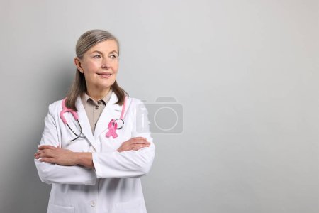 Mammologist with pink ribbon on gray background, space for text. Breast cancer awareness