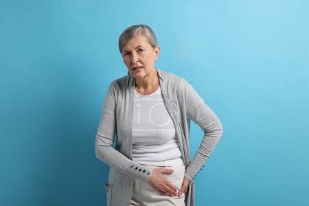 Photo for Arthritis symptoms. Woman suffering from hip joint pain on light blue background - Royalty Free Image