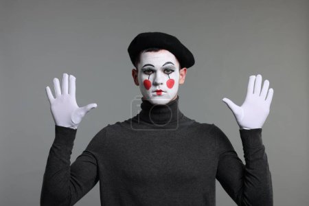 Mime-Künstler in Baskenmütze posiert auf grauem Hintergrund