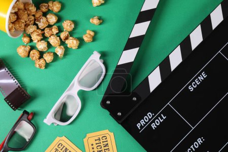 Flache Liegekomposition mit Klappbrett, Kinokarten und 3D-Brille auf grünem Hintergrund