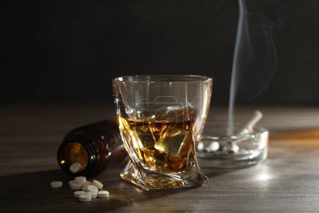 Alkoholsucht. Whiskey im Glas, Tabletten und Zigaretten auf Holztisch