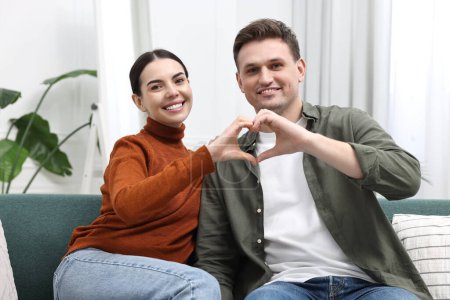 Téléchargez les photos : Couple heureux faisant coeur avec les mains à la maison - en image libre de droit