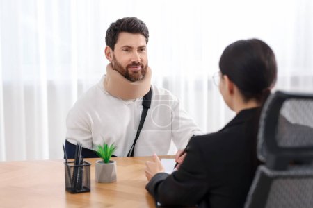 Injured man having meeting with lawyer in office, selective focus