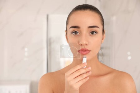 Mujer con herpes aplicando crema en los labios sobre un fondo borroso. Espacio para texto