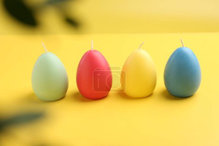 Téléchargez les photos : Bougies colorées en forme d'oeuf sur fond jaune. Décor de Pâques - en image libre de droit