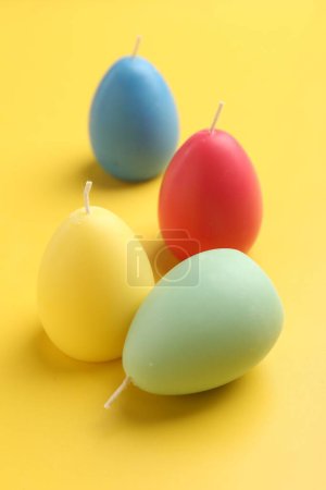 Téléchargez les photos : Bougies colorées en forme d'oeuf sur fond jaune. Décor de Pâques - en image libre de droit