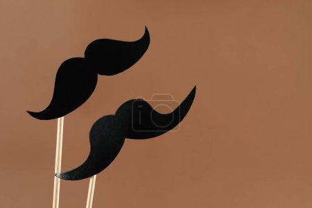 Téléchargez les photos : Faux papier moustaches accessoires de fête sur fond brun clair, espace pour le texte - en image libre de droit
