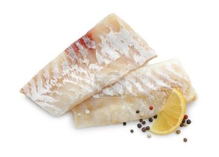 Foto de Filetes frescos de bacalao crudo con granos de pimienta y limón aislados en blanco, vista superior - Imagen libre de derechos